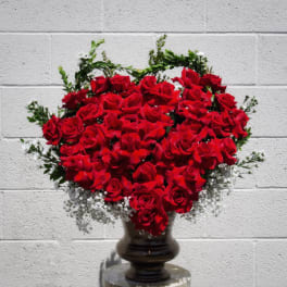 Heart-shaped arrangement of red roses in a dark vase