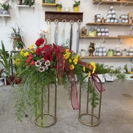 Casket spray with red, yellow, and white flowers and burgundy ribbon