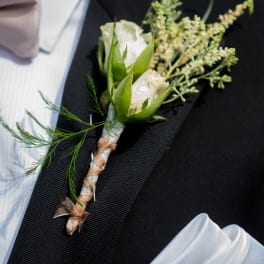 White rose boutonniere on a black suit jacket
