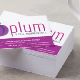 Stack of Plum Floral Arrangements business cards beside a star-patterned mug