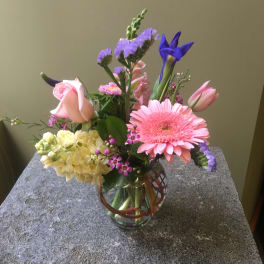 Mixed bouquet in a glass vase with pink, purple, and yellow flowers