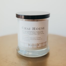 A glass jar candle with a black lid and white label