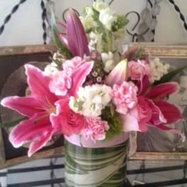 Pink lilies and carnations arranged in a striped vase