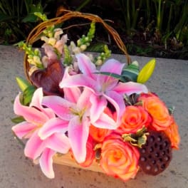 Pink lilies and orange roses in a basket with a woven handle