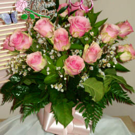 Pink roses arranged in a vase with a Mother's Day topper and butterfly picks