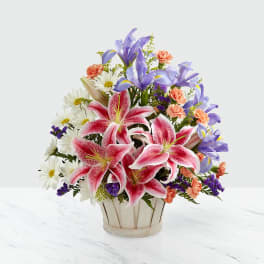 Bouquet of pink lilies, purple irises, and white daisies in a vase