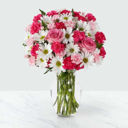Pink roses, carnations, and white daisies in a clear glass vase