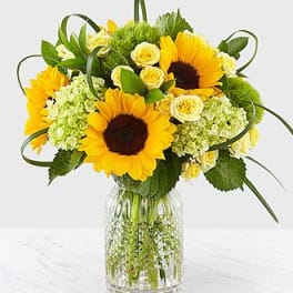 Sunflower and yellow rose bouquet in a clear glass vase