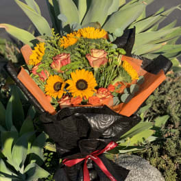 Bouquet of orange sunflowers and roses wrapped in black paper