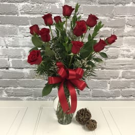 Red roses in a clear glass vase with a red ribbon bow