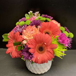 Bright mixed flower arrangement in a white textured vase