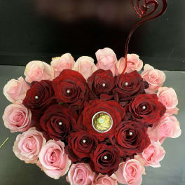 Heart-shaped rose arrangement with pink and red roses and a heart topper