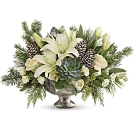 White lilies and pinecones arranged in a silver pedestal bowl