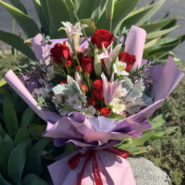 Bouquet of red roses and white lilies wrapped in pink paper