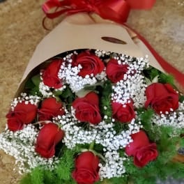 Bouquet of red roses with white baby's breath in kraft paper and a red ribbon