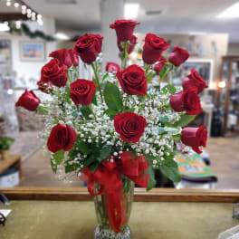 Red roses arranged in a clear glass vase with a red ribbon