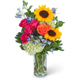 Bouquet of sunflowers, roses, and blue flowers in a glass vase
