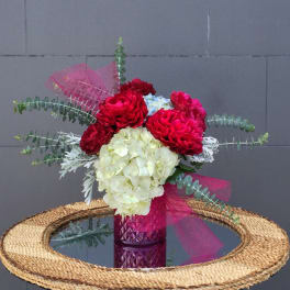 Bouquet of red and white flowers in a pink glass vase