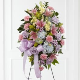 Standing floral spray with pink lilies, carnations, and lavender roses on a ribboned easel