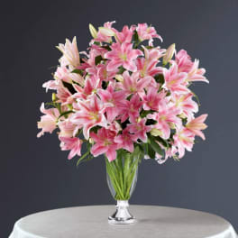 Pink lilies arranged in a clear glass vase on a table