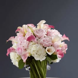 Pink and white bouquet of roses and calla lilies in a clear vase