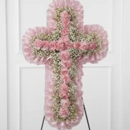 Pink floral cross-shaped standing spray on an easel