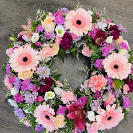 Circular floral wreath with pink gerberas, roses, and carnations