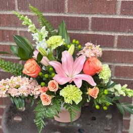 Pink lily and peach rose arrangement in a pink vase