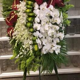 Tall standing floral spray with yellow lilies, burgundy anthuriums, and white orchids