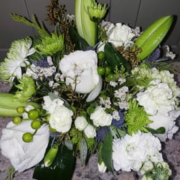 Compact arrangement of white roses, lilies, and carnations with green accents