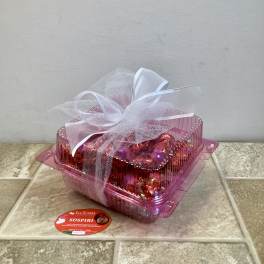Pink gift box tied with white ribbon and tulle, with a candy label in front