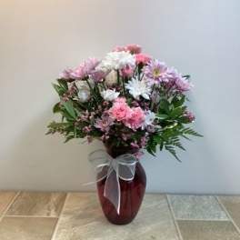 Pink and white mixed bouquet in a red glass vase with a sheer bow