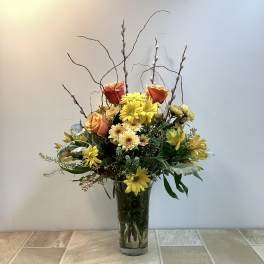 Mixed bouquet of yellow and orange flowers in a clear glass vase