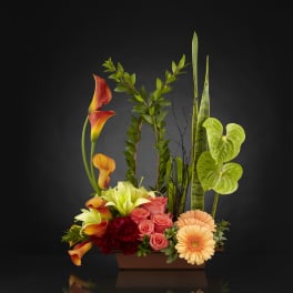 Mixed floral arrangement with calla lilies, roses, and gerbera daisies in a rectangular vase