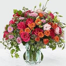 Mixed pink and orange flower bouquet in a glass vase