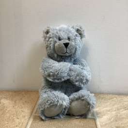 Gray plush teddy bear sitting upright with paws crossed