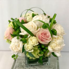 Bouquet of white and pink roses with green accents in a glass vase