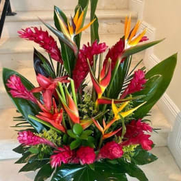 Tall tropical arrangement with red and orange flowers and large glossy leaves