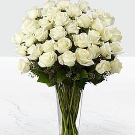Tall clear vase filled with a large bouquet of white roses