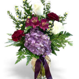 Bouquet of white roses, purple hydrangea, and burgundy flowers in a glass vase
