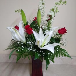 White lilies and red roses arranged in a tall vase