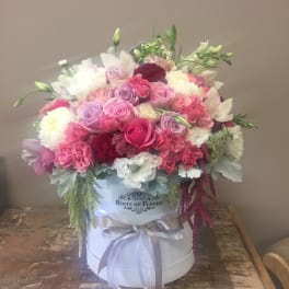Pink and white mixed flower arrangement in a white hat box with ribbon