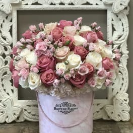 Pink and white rose arrangement in a round hatbox