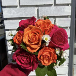 Handheld bouquet of orange and pink roses with small white daisies