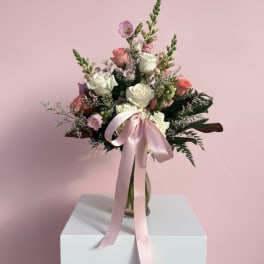 Pink and white rose bouquet in a glass vase with a satin ribbon