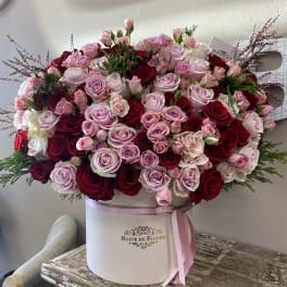 Large pink and red rose arrangement in a round hat box with ribbon