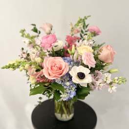 Pastel bouquet of roses, anemones, and hydrangeas in a glass vase