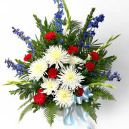 Red and white flowers in a white vase with a blue ribbon