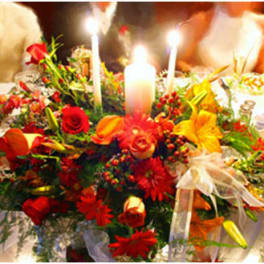 Low red, orange, and yellow floral centerpiece with candles on a formal banquet table