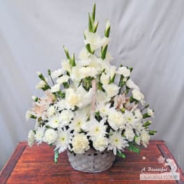 White floral arrangement in a woven basket with tall blooms